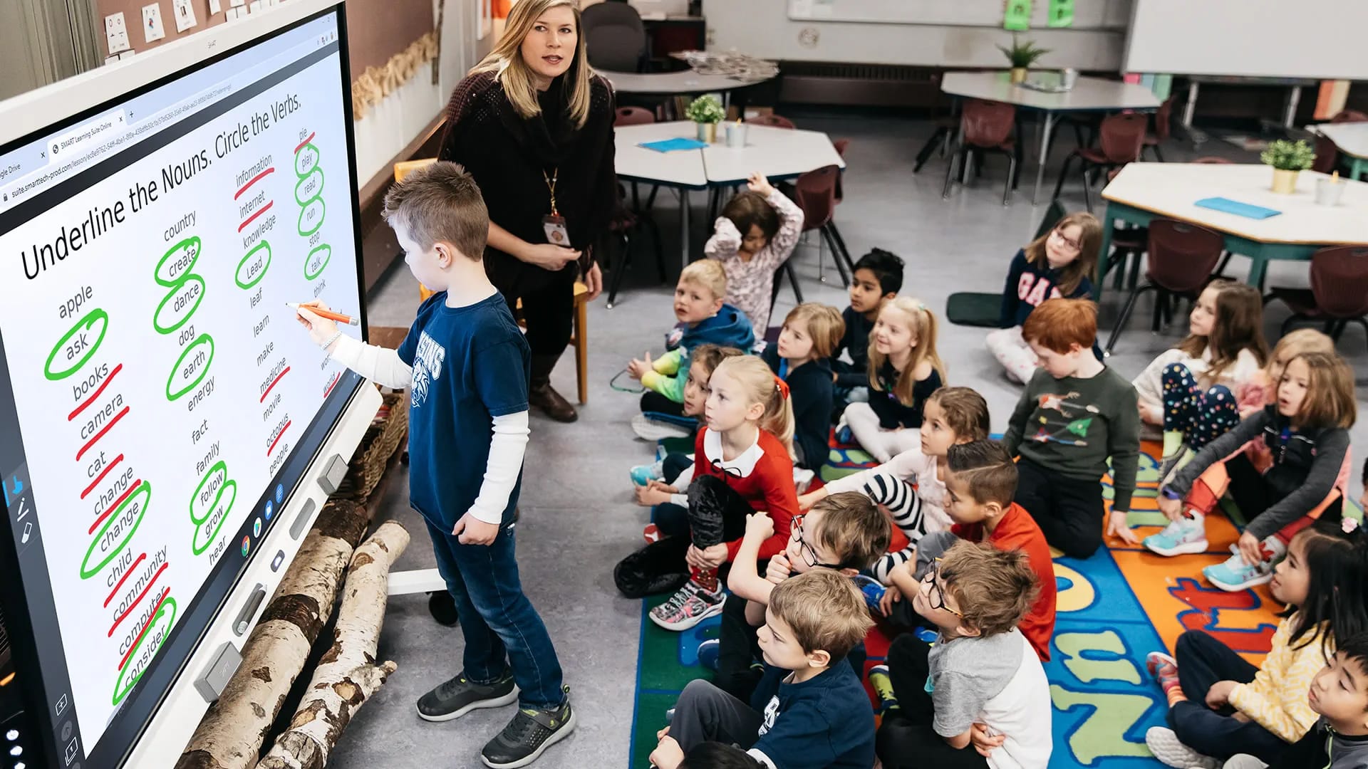 Kinderen in een klaslokaal rond een digitaal schoolbord