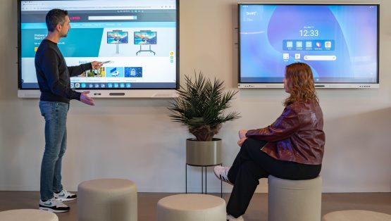 Twee personen gebruiken een SMART Board tijdens een interactieve sessie.