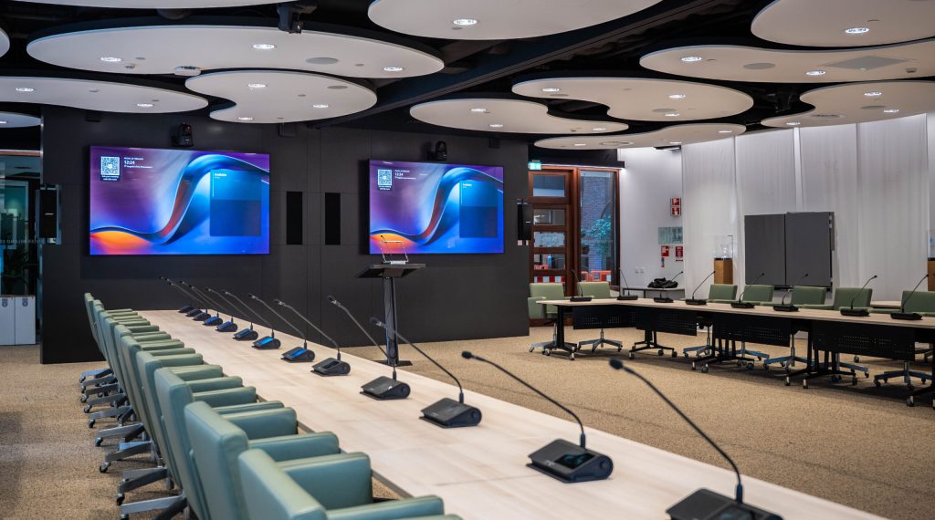 Vergaderzaal bij Waterschap Rivierenland met schermen voor roomsignage en microfoons