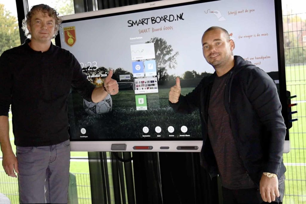 Marcel en Wesley Sneijder staan voor een digibord. Wesley Sneijder heeft een digibord gekocht voor de voetbal.