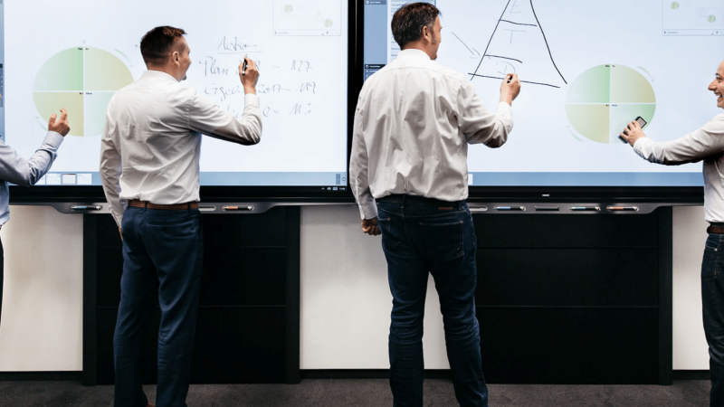 SMART Meeting Pro software in gebruik. Een groepje mensen staat voor 2 SMART Boards en maakt gebruik van de SMART Meeting Pro Software