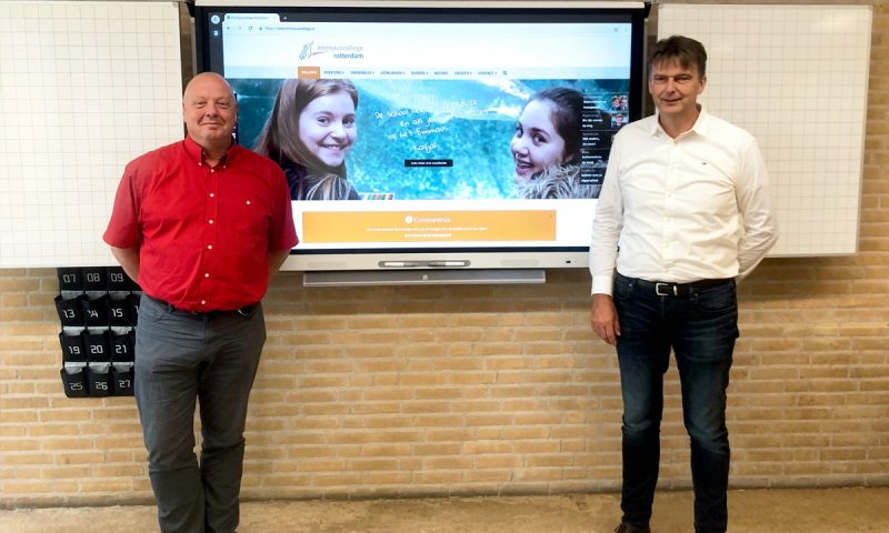 Twee personen die tevreden voor een SMART Board opstelling staan.