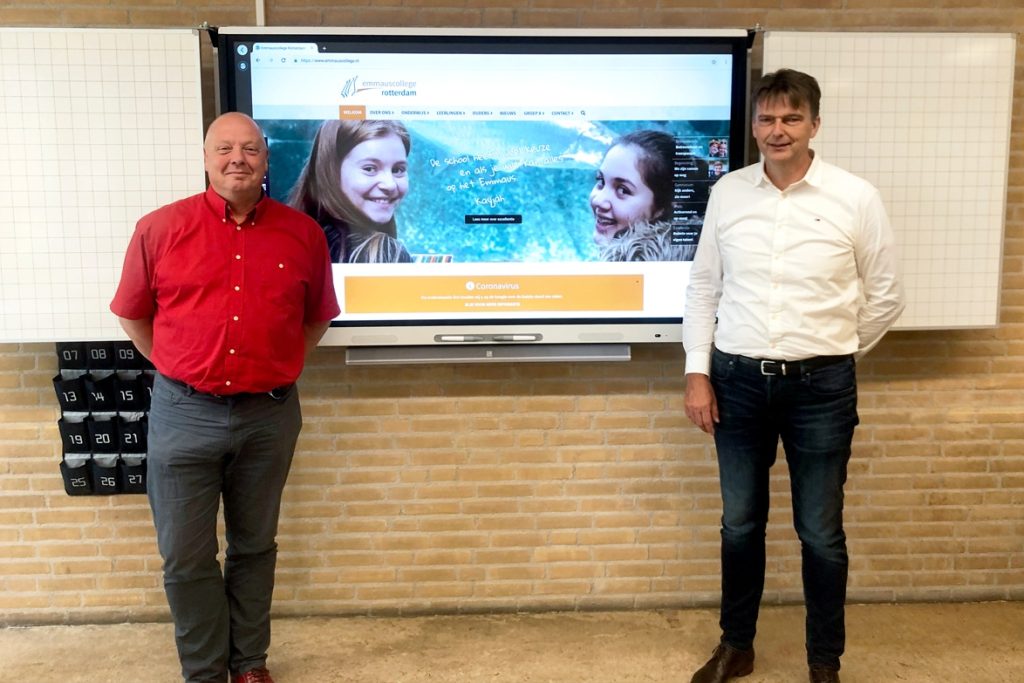 Twee personen die tevreden voor een SMART Board opstelling staan.