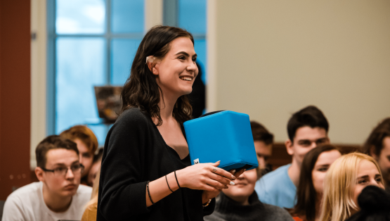 Een vrolijke studente houdt de Catchbox vast en is actief aan het meedoen in de les.